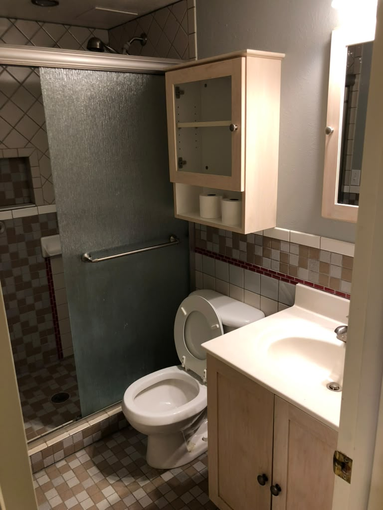 Bathroom before repainting with dated tile and gray walls