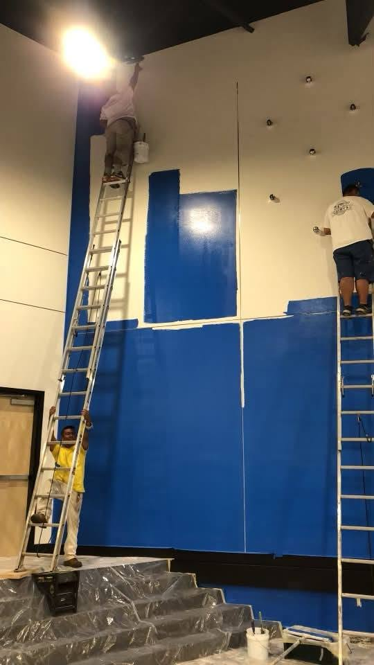 Luis Trasviña Painting Services crew on ladders painting a tall commercial wall blue