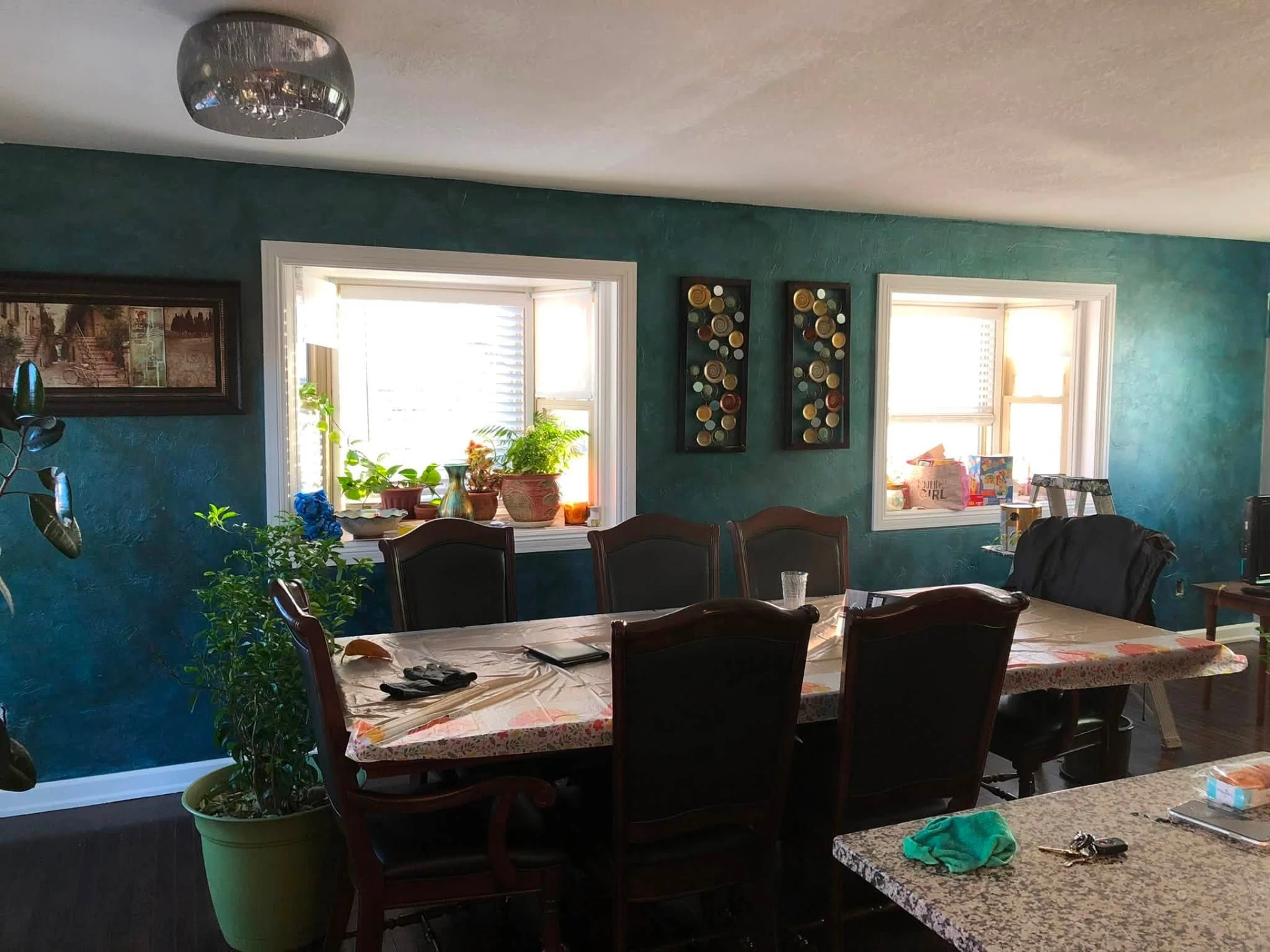 Dining room with a deep teal textured accent wall and crisp white trim