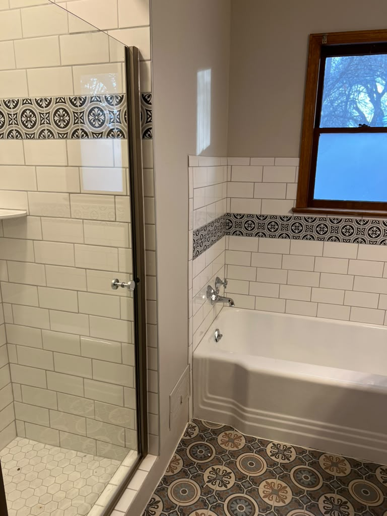 Remodeled bathroom with white subway tile, patterned accent tile, and soaking tub