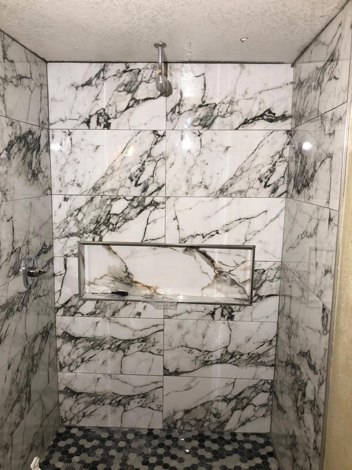 Marble tile shower with recessed niche and hexagon mosaic floor