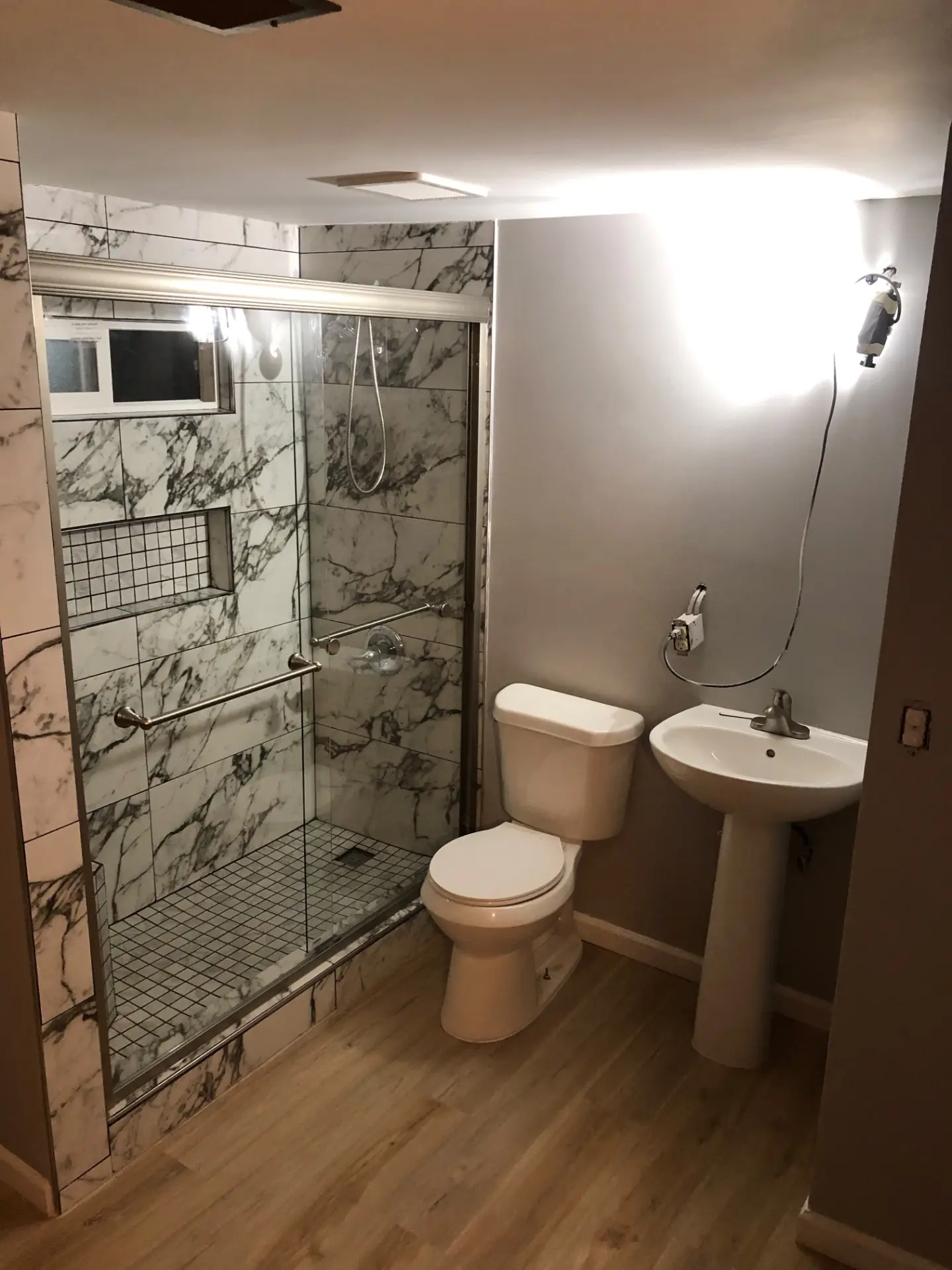 Basement bathroom with marble tile shower, pedestal sink, and warm painted walls