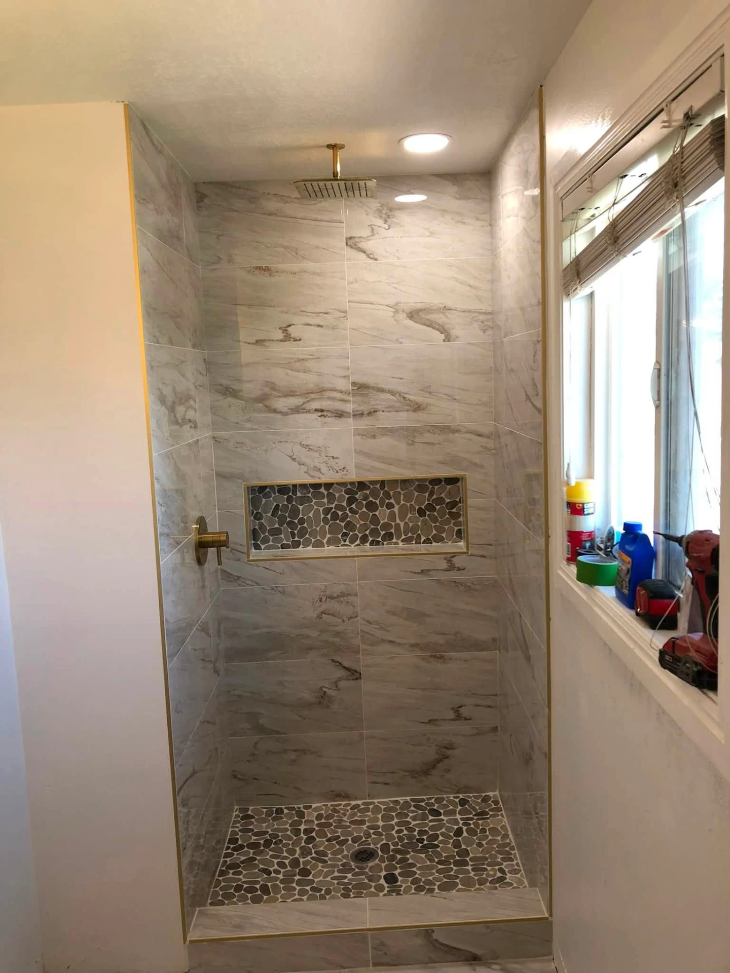 Freshly finished marble tile shower with gold trim details