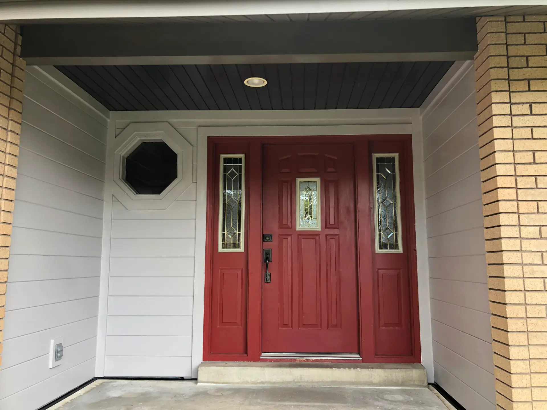Front entry with a deep red painted door and light gray siding