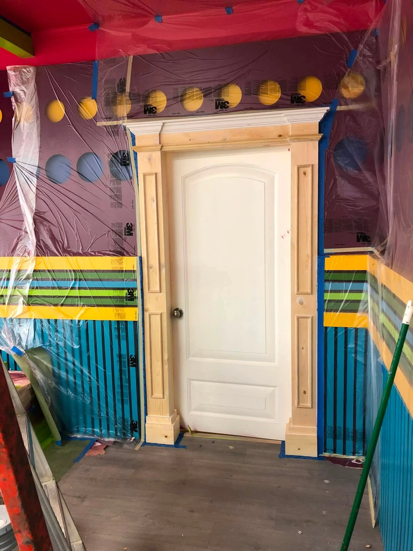 Masked doorway and trim prepped before spraying in a colorful commercial interior